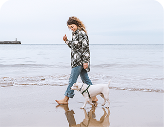 femme qui marche avec un chien sur la plage